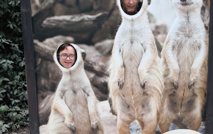 Ein Bild von zwei Besuchern die sich hinter eine dekorierten Wand fotografieren lassen.