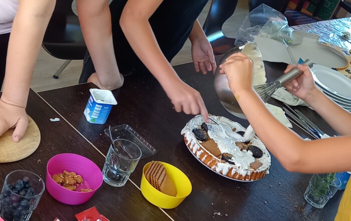 Mehrere Mädchen dekorieren eine Torte.