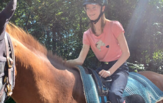 Ein Mädchen sitzt auf dem Pferd.