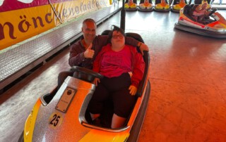 Ein Foto von Betreuer und Bewohnerin auf dem Autoscooter